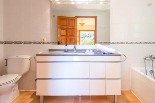 a white bathroom with a sink and a toilet at Villa Rosa in Calonge