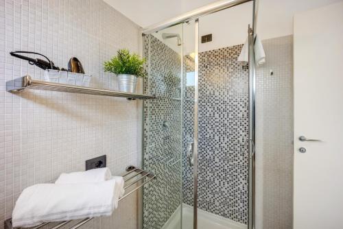 a bathroom with a glass shower with white tiles at Appartamento Monolocale Rebi in Imperia