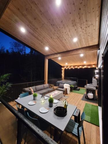 a patio with a table and chairs on a deck at Chalet Le Select - Private Spa with River View in Les Éboulements