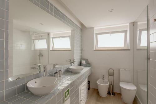 a white bathroom with two sinks and two toilets at Cascais Bay Terrace I in Cascais