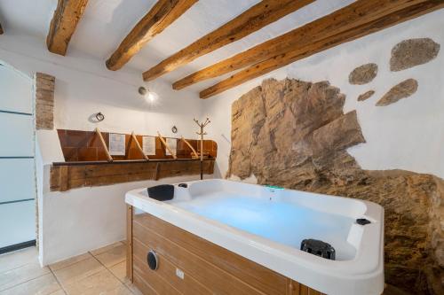 a large bath tub in a bathroom with a stone wall at El racó de les escales in Tivissa