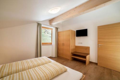 a bedroom with a bed and a television in it at Ferienwohnung Edelweiss in Pfelders