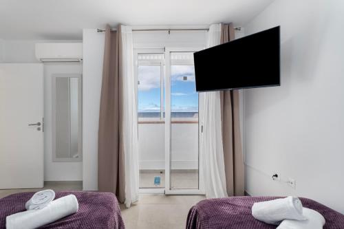 a room with two beds and a flat screen tv at Villa Atlantico in Candelaria