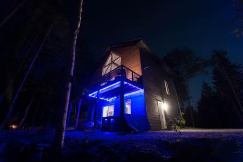 a house with blue lights on it at night at Luft Skift Spa - Waterfront & Private Spa in Lac-aux-Sables