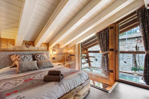 a bedroom with a large bed and a large window at Lo Pailler de Mamma e Pappa in Valsavarenche