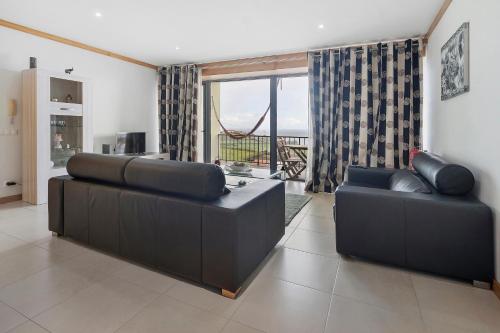 a living room with two black couches and a window at Quinta da Faya in Angra do Heroísmo