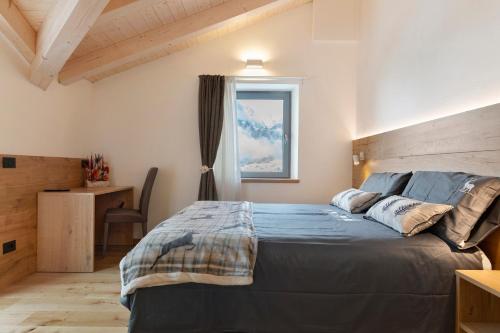 a bedroom with a bed with a blue comforter and a window at Alpen Blumen in San Lorenzo in Banale