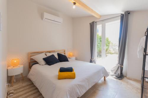 a white bedroom with a large bed with a yellow pillow at Villa chardonnay in Pradons