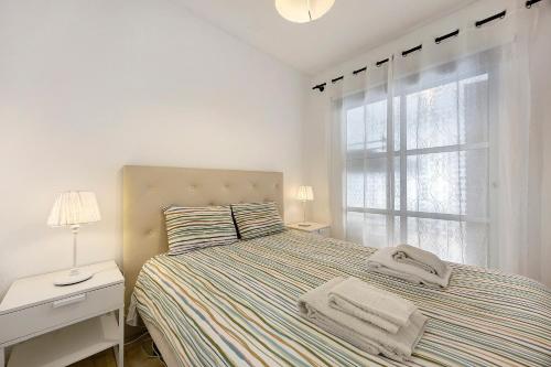 a white bedroom with a bed and a window at Casa Vitorino in Sagres