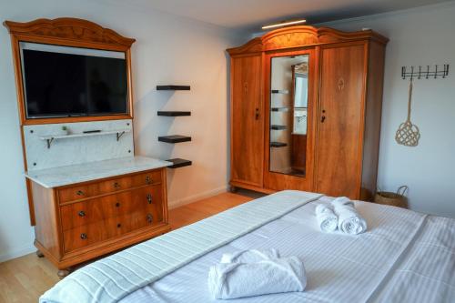 a bedroom with a bed with a dresser and a television at Second Home in Birlenbach