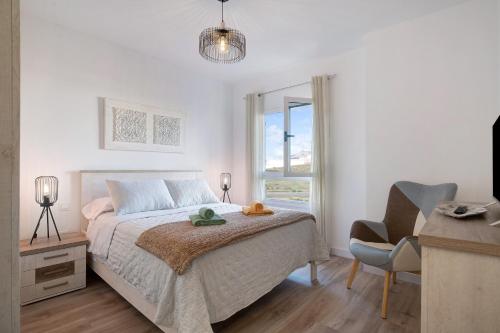 a bedroom with a bed and a chair and a window at Casa Reguemar in Arrecife