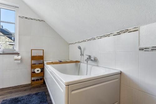 a white bathroom with a tub and a window at Ferienhaus Glücksschmiede in Schmallenberg