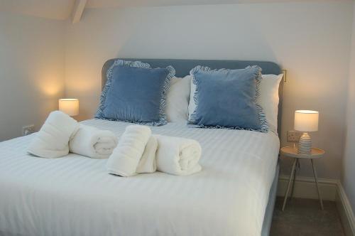 a white bed with blue pillows and two lamps at Morwendon House with Sea View in Llanaber