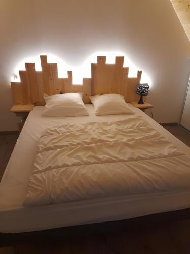 un grande letto bianco con una grande testiera in legno di Gite Ranch a Tirepied