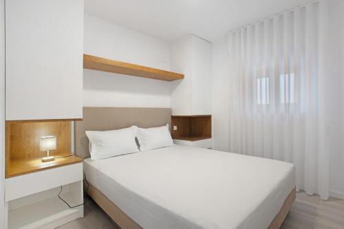 a bedroom with a white bed and a window at T3 São Martinho do Porto in São Martinho do Porto
