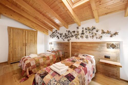 two beds in a room with wooden ceilings at Villa Lice - Vigneto in Casarza Ligure