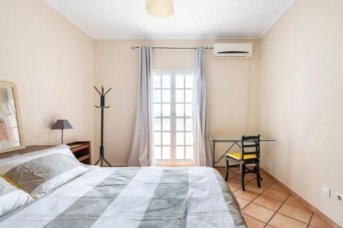 ein Schlafzimmer mit Bett, Schreibtisch und Fenster in der Unterkunft Villa Laforge in Carmona