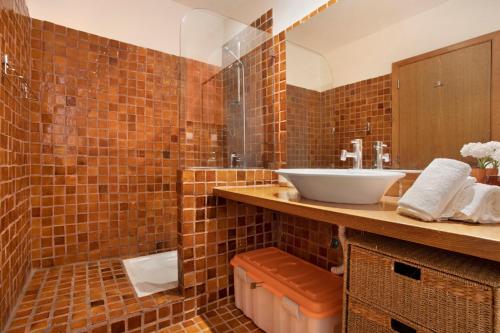 a brown tiled bathroom with a sink and a shower at Arrancada 7 in São Lourenço
