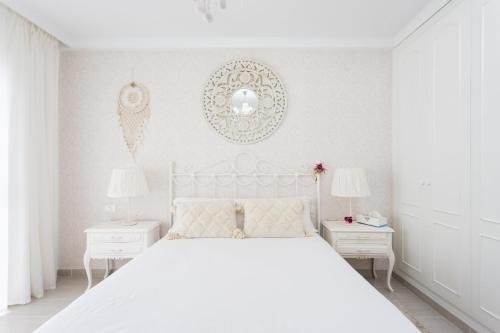 a white bedroom with a white bed and two white tables at Sunset Costa Adeje Oceanview in Adeje