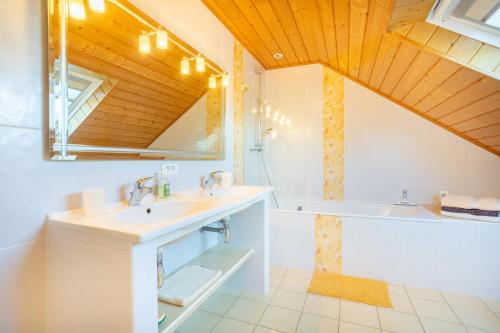 a bathroom with a sink and a tub and a mirror at Maison Indépendante Sur Jardin in Mahalon
