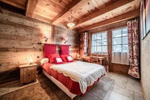 a bedroom with wooden walls and a bed with red pillows at la ferme de la Vora in Châtel