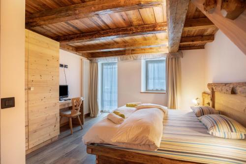 a large bed in a room with wooden ceilings at Chalet Osmar Appartamento 2 in Campitello di Fassa