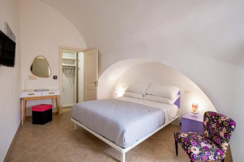 a bedroom with a white bed and a chair at Dimora Egilò - Violet in Nardò
