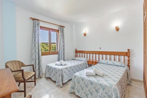 a bedroom with two beds and a table and a window at Apartamento La Cabanya 3a in Canyamel