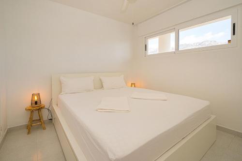 a white bedroom with a large bed with a window at Costabella Altea in Altea