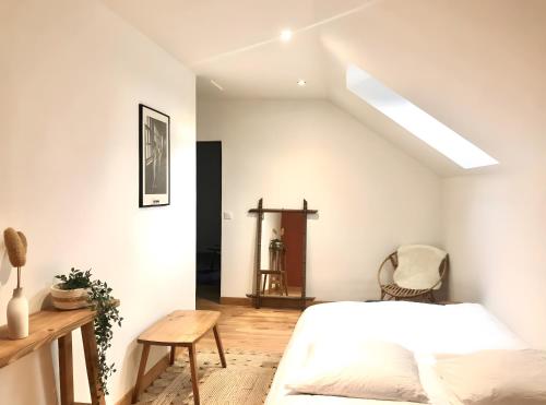 a white bedroom with a bed and a table at Gite Fleur De Miel in Saffloz