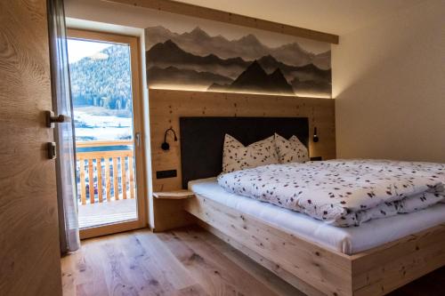 a bedroom with a bed with a mountain mural on the wall at Kieserhof Apartment Berg in Terento