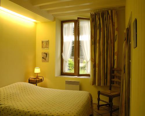 a bedroom with a bed and a window and a chair at Haras de la fontaine Diva in Poligny
