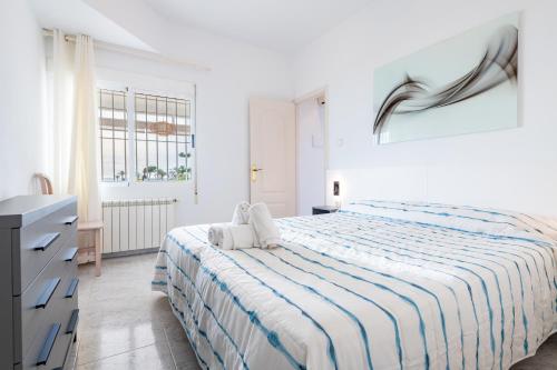 a white bedroom with a bed with a striped blanket at Casa Vesalia in Vinarós
