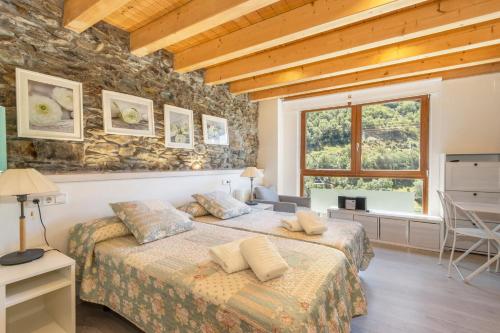 a bedroom with two beds and a stone wall at Casa Guillem Completa in Tavascan