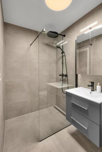a bathroom with a glass shower and a sink at Sunny Central in Kristiansand