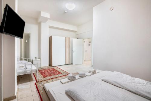 a white bedroom with a bed and a flat screen tv at Aldars Urban Loft Suite No.8 in Munich