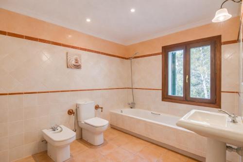 a bathroom with a toilet and a tub and a sink at Son Grau in Alaró
