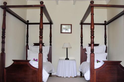 a bedroom with two four poster beds with white pillows at De Kothuize 16 in Graaff-Reinet