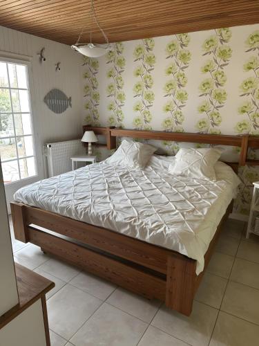 a bedroom with a large bed with a wooden frame at Maison d'Hôtes - La Marée Hôtes in Piriac-sur-Mer