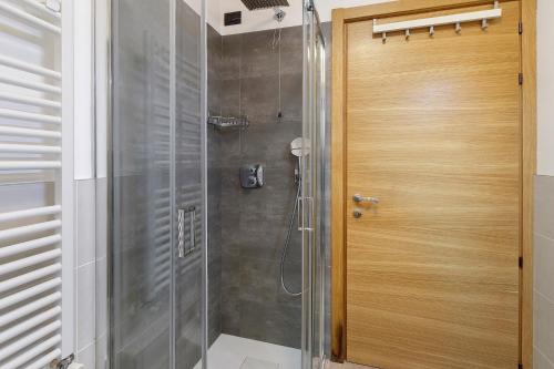 a shower with a wooden door in a bathroom at Appartamenti Via Dell'Asilo in Valdidentro