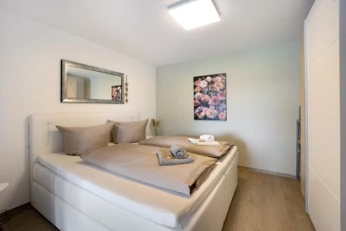 a bedroom with a large white bed with a mirror at Landliebe – Seenähe & Grüntenblick in Petersthal