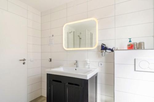 a white bathroom with a sink and a mirror at Ferienwohnung Rothmund in Überlingen
