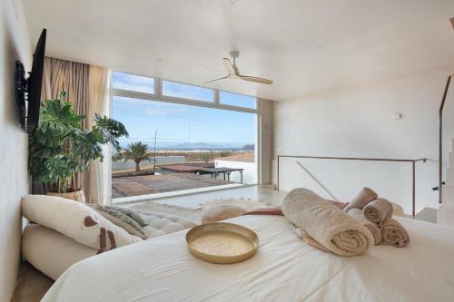 a bedroom with a white bed with a large window at Casa Marea - Villa Con Jacuzzi in Corralejo