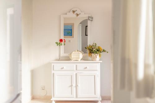 a white cabinet with a mirror and flowers on it at Apartamento Cala en Forcat 34 in Cala en Blanes