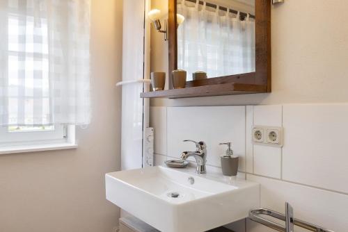 a bathroom with a white sink and a mirror at Ferienwohnung im alten Vierseithof in Friedewald