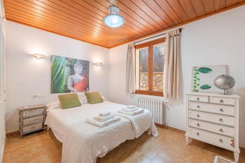 a bedroom with a bed and a dresser and a window at Villa Ses Basses in Mancor del Valle