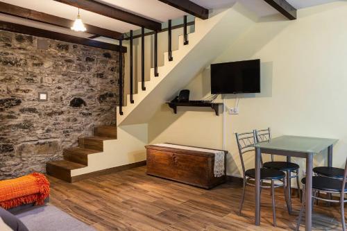 a living room with a table and a tv and stairs at Villa Rústica - Casa da Lurdes in Ribeira Brava