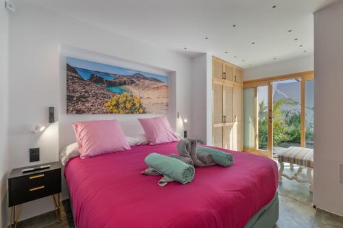 a bedroom with a large pink bed with two stuffed animals on it at El Alcaidón in Tías