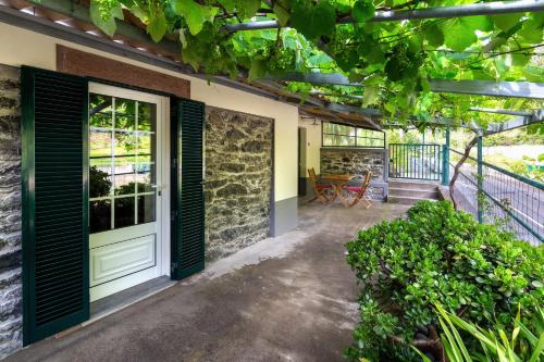 an outdoor patio with a door and some plants at Villa Rústica - Casa da Lurdes in Ribeira Brava