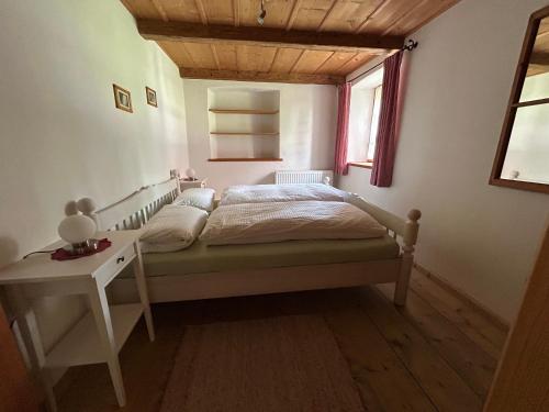 a bedroom with a bed and a table and a window at Ferienwohnung Filser in Unterammergau